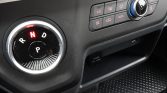 Circular gear selector dial showing R N D and P in a car dashboard, with climate controls and a 12V power outlet below.