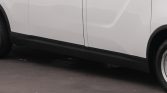 Side view of a white van showing the lower black trim and wheel at the rear-right edge of the image