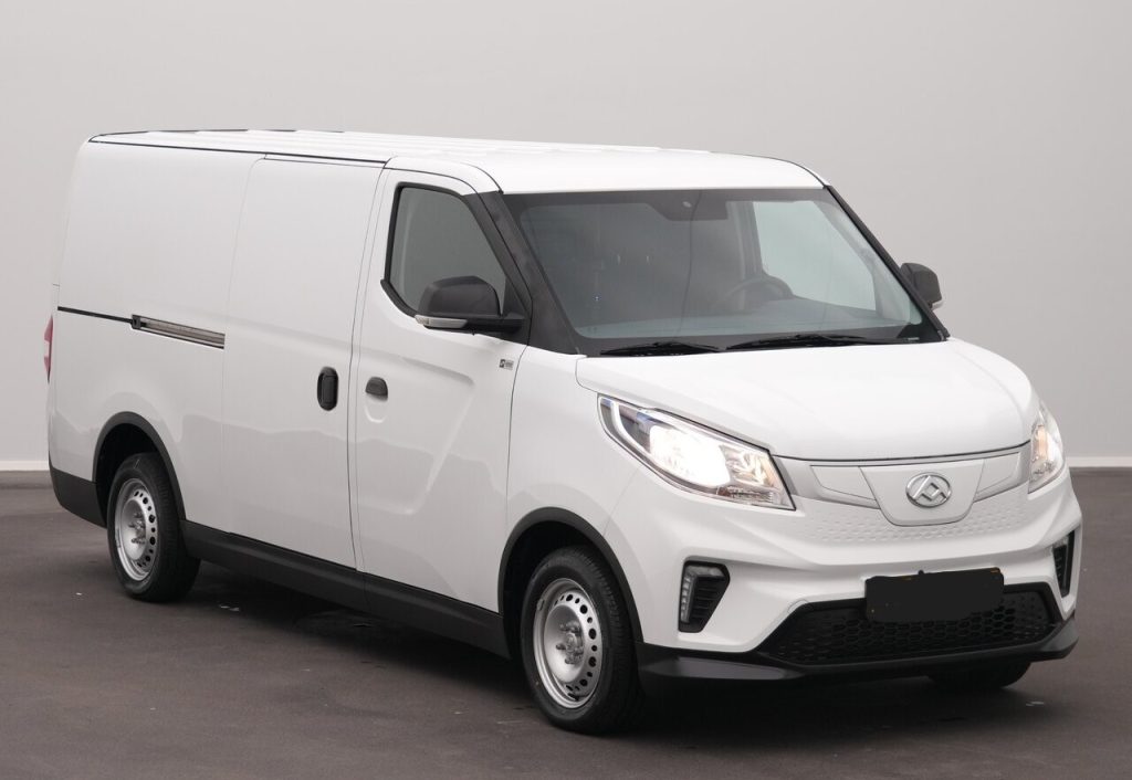 Front-left view of a white commercial cargo van with black grille and headlights, parked indoors with no branding visible to communicate its purpose as a delivery vehicle.