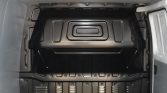Empty metal cargo space inside a van with ribbed floor and side walls