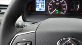 Close-up of a car steering wheel with illuminated speedometer and digital display behind.