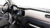 Interior view of a car dashboard with steering wheel, digital displays, and center console touchscreen in focus.