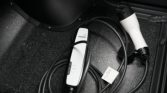 EV charging cable and white control box lying on a car floor mat near the trunk opening.