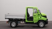 Small bright green flatbed truck with open cabin and single-seat driver area, parked indoors