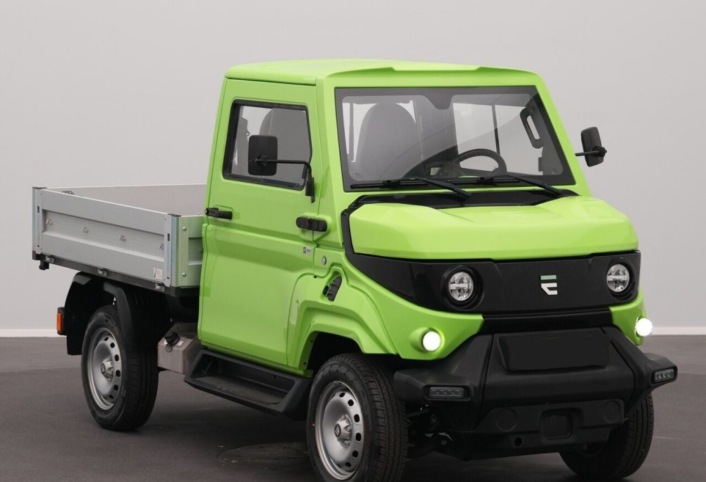 Front three-quarter view of a bright lime-green utility pickup truck with a flatbed, black bumper and round headlights, indoors.