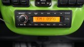 Car stereo unit set in a bright green dashboard, showing FM1 89.70 on the orange display.