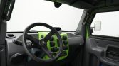 Interior of a vehicle cabin focusing on a bright green dashboard and black steering wheel from the driver's perspective.