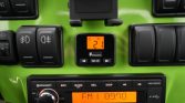Green vehicle dashboard featuring a central orange digital climate display reading 21°C, surrounded by switches and a Continental radio unit below.