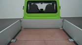 Rear view of a bright green truck with an empty flatbed and gray side rails