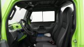 Interior of a lime-green truck cab with black bucket seats, steering wheel, and dashboard seen from the open door