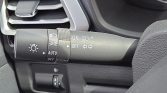 Multifunction car stalk showing headlight controls (AUTO, fog lights) and turn signal indicators on the steering column as seen in a vehicle interior.