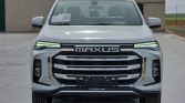 Front view of a white Maxus pickup truck with a bold chrome grille and LED daytime running lights.