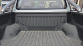 Pickup truck bed with a textured, ridged liner and wheel wells on both sides, viewed from the tailgate area.
