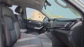Interior view of a modern car showing the front seats, dashboard, and center console with a touchscreen display, steering wheel, and black upholstery with red stitching