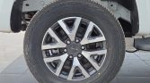 Close-up of a black alloy wheel with a Maxxis tire mounted on a white vehicle, showing the tread and spoke design.