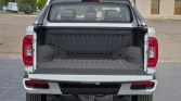 Rear view of a white pickup with the tailgate down, showing an empty cargo bed with ribbed liner.