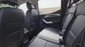 Leather-textured rear car seat view with headrests and door panel, showing spacious back row and seat belts in a modern SUV interior