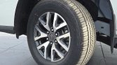 Close-up of a car tire mounted on a silver and black alloy wheel in a wheel well on a vehicle, showing the tread pattern and fender.