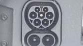 Close-up of a vehicle charging port with multiple circular connectors under a protective cover.