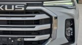 Front view of a white pickup with a large chrome grille and LED daytime running lights in the headlight area.