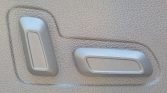 Two plastic car seat adjustment levers on the side of a textured seat.