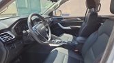 Interior of a modern SUV showing the driver and front passenger seats, steering wheel, and center console with gear shifter.