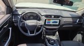 Interior of a modern car cockpit with steering wheel, instrument cluster, and a central touchscreen displaying a blue pickup image.