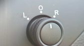 Rotary control on a car dashboard labeled L, O, R (left, off, right) with the knob set toward the center position.