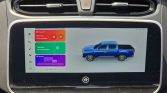 In-car touchscreen showing a blue pickup truck graphic with colorful widgets on the left (Music, Phone, Photos) and a vehicle illustration on the right side of the screen.