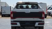 Rear view of a white SAIC Motor T90 EV pickup truck in a parking lot.