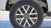 Close-up of a vehicle wheel: alloy rim with a black-and-silver design and visible brake components behind the tire.