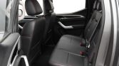Rear passenger seats of a black leather SUV interior with red contrast stitching and three seat belts.