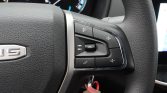 Close-up of steering wheel controls: volume up/down, mute, source button, and phone hang-up button on a car's right-side cluster.