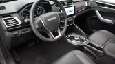 Interior of a modern car showing the driver's cockpit: steering wheel, digital gauge cluster, and center touchscreen display.
