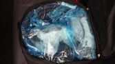 Open black travel bag with a blue plastic bag and bubble wrap inside.