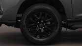 Close-up of a black alloy wheel and tire on a dark gray vehicle, resting on a garage floor