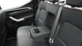 Rear car seat with a fold-down center armrest featuring two cup holders and red-stitched black leather upholstery