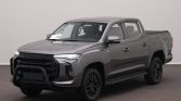 Gray Maxus pickup truck with black grille and front bull bar, four-door crew cab, parked indoors.