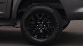 Close-up of a black alloy wheel and tire on a dark vehicle, with brake components faintly visible through the spokes.