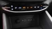 Close-up of a car's center console climate control panel with illuminated icons (fan, airflow, recirculation, A/C) and two USB ports below, plus a circular power socket nearby.