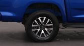 Blue pickup truck wheel with a silver alloy rim and visible tire treads, under the blue fender.