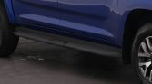 Blue pickup truck side view showing a grey running board beneath the doors and part of the wheel.