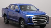 Front three-quarter view of a blue Maxus pickup truck with a bold chrome grille and crew cab inside a studio setting