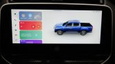 In-car touchscreen showing colorful app tiles on the left and a blue pickup truck graphic on the right.