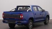 Blue pickup truck viewed from rear-right, with a silver roll bar and bold MAXUS tailgate emblem in a showroom setting