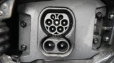 Close-up of an electric vehicle charging inlet with two circular sockets (top multi-pin, bottom dual-pin).