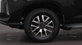 Close-up of a black vehicle's front wheel with a silver alloy rim and visible tire tread.