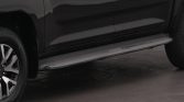 Side view of a dark pickup truck with a silver running board and a visible front wheel on the left.
