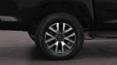Close-up of a silver alloy wheel and tire on a black vehicle, showing the fender and undercarriage area.