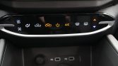 Inline car climate control panel with illuminated icons: fan, air flow modes, recirculation, power, A/C, defrost indicators, and temperature up/down on the right.